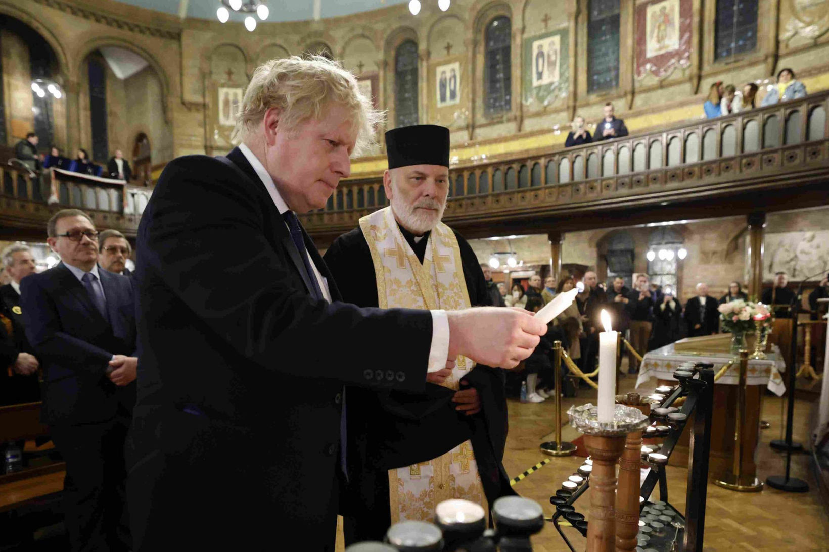 Британський прем’єр-міністр Борис Джонсон запалює свічку під час візиту до української католицької катедри Пресвятої Родини в Лондоні, 27 лютого 2022 року, фото: PA Images via Alamy